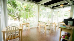 A bright, open dining area with wooden tables and chairs, large windows, and a view of greenery outside. - Belle Garden Yillan Villa (Dongshan)