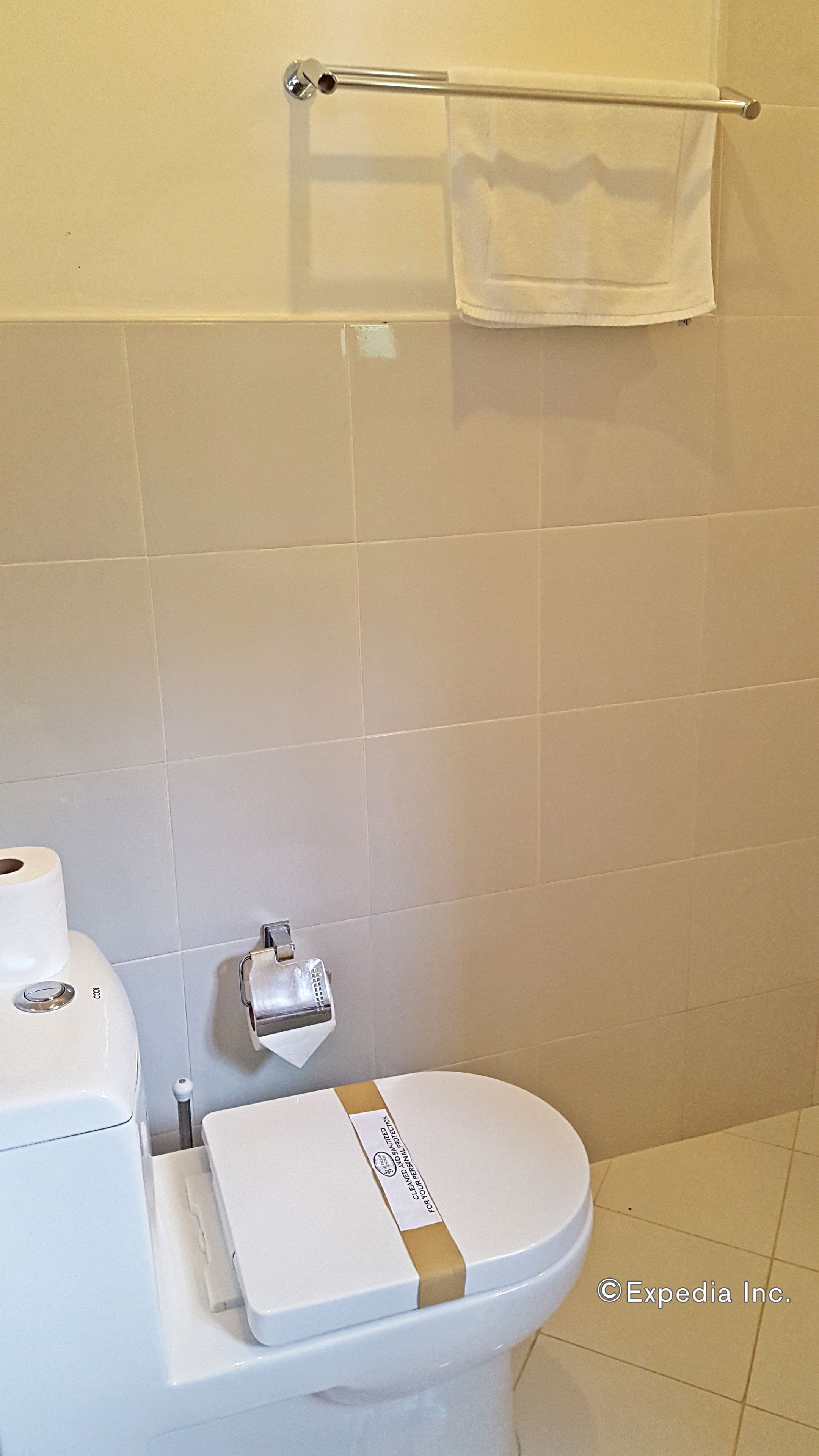 A bathroom with a toilet, a paper towel dispenser, and a towel rack.
