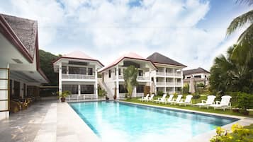 Una piscina al aire libre, sombrillas, sillones reclinables de piscina