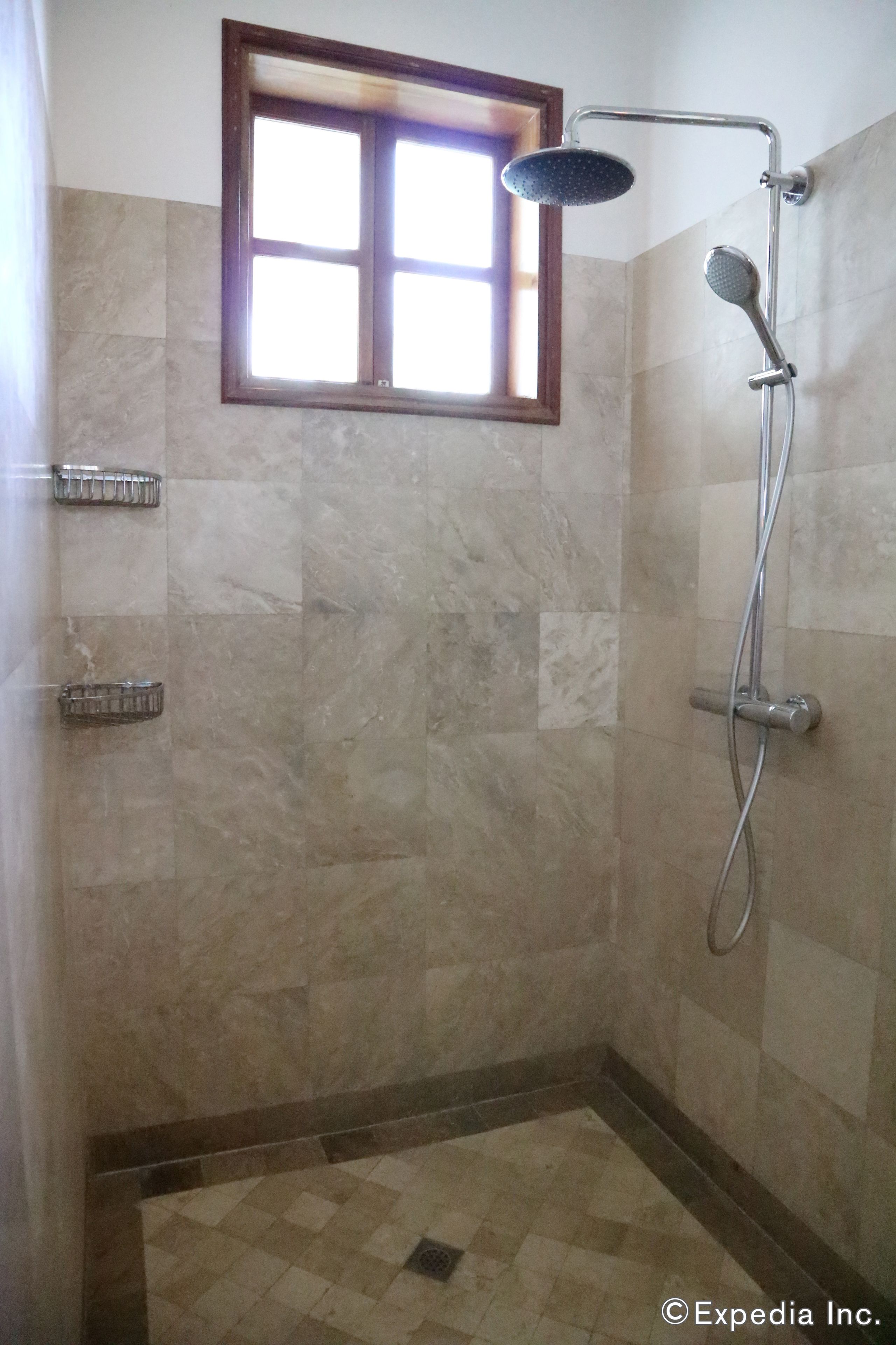 Une salle de bain avec une douche, une fenêtre et des murs carrelés.
