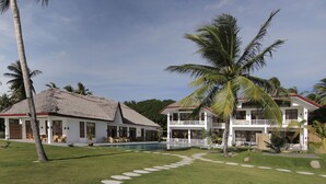 A two-story house with a pool, surrounded by palm trees and a well-maintained lawn.