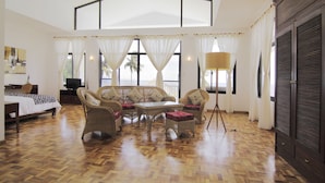 A spacious room with a large bed, wicker furniture, and a television.