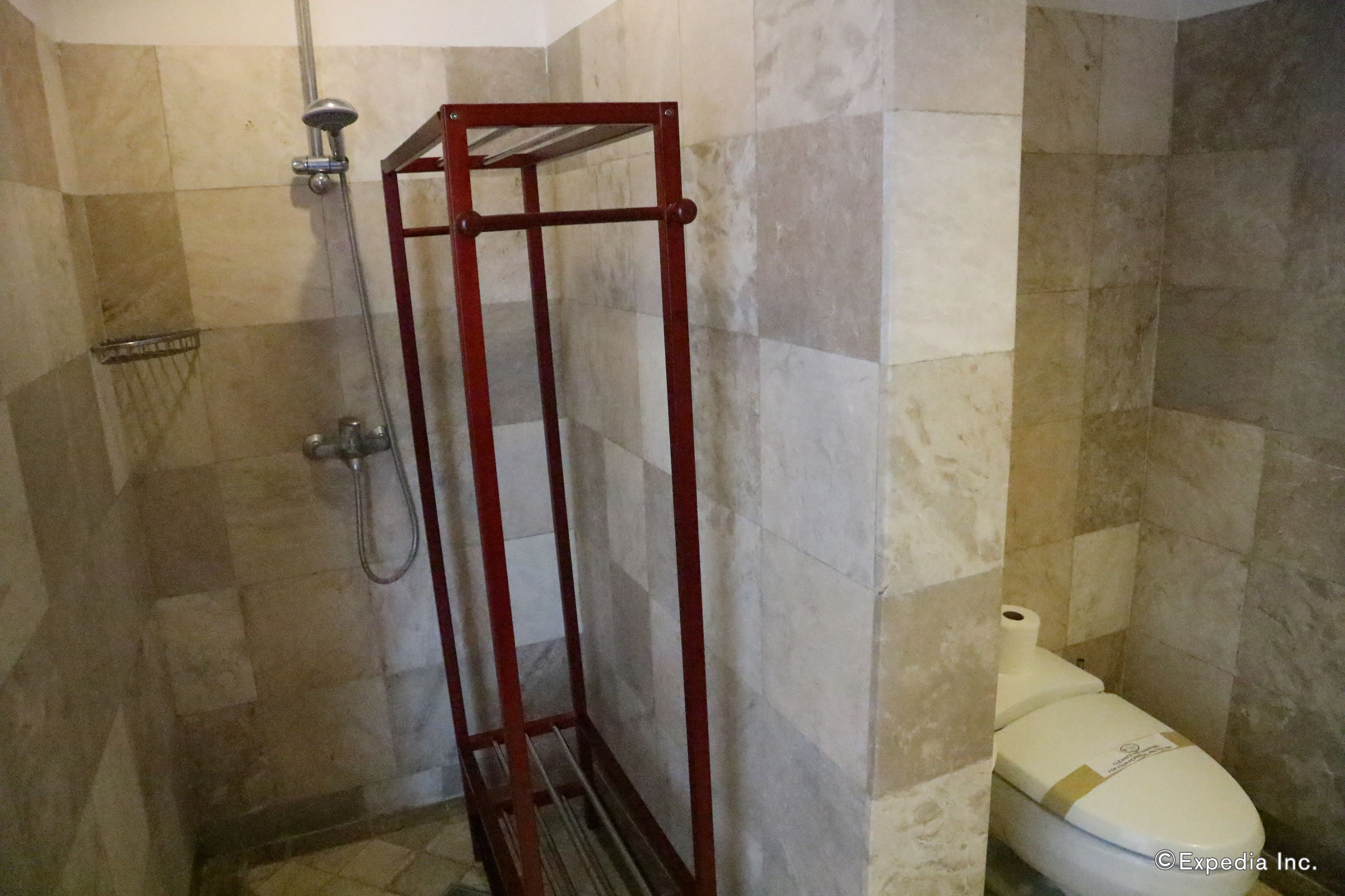 Une salle de bain avec une douche, des toilettes et un carrelage au sol.