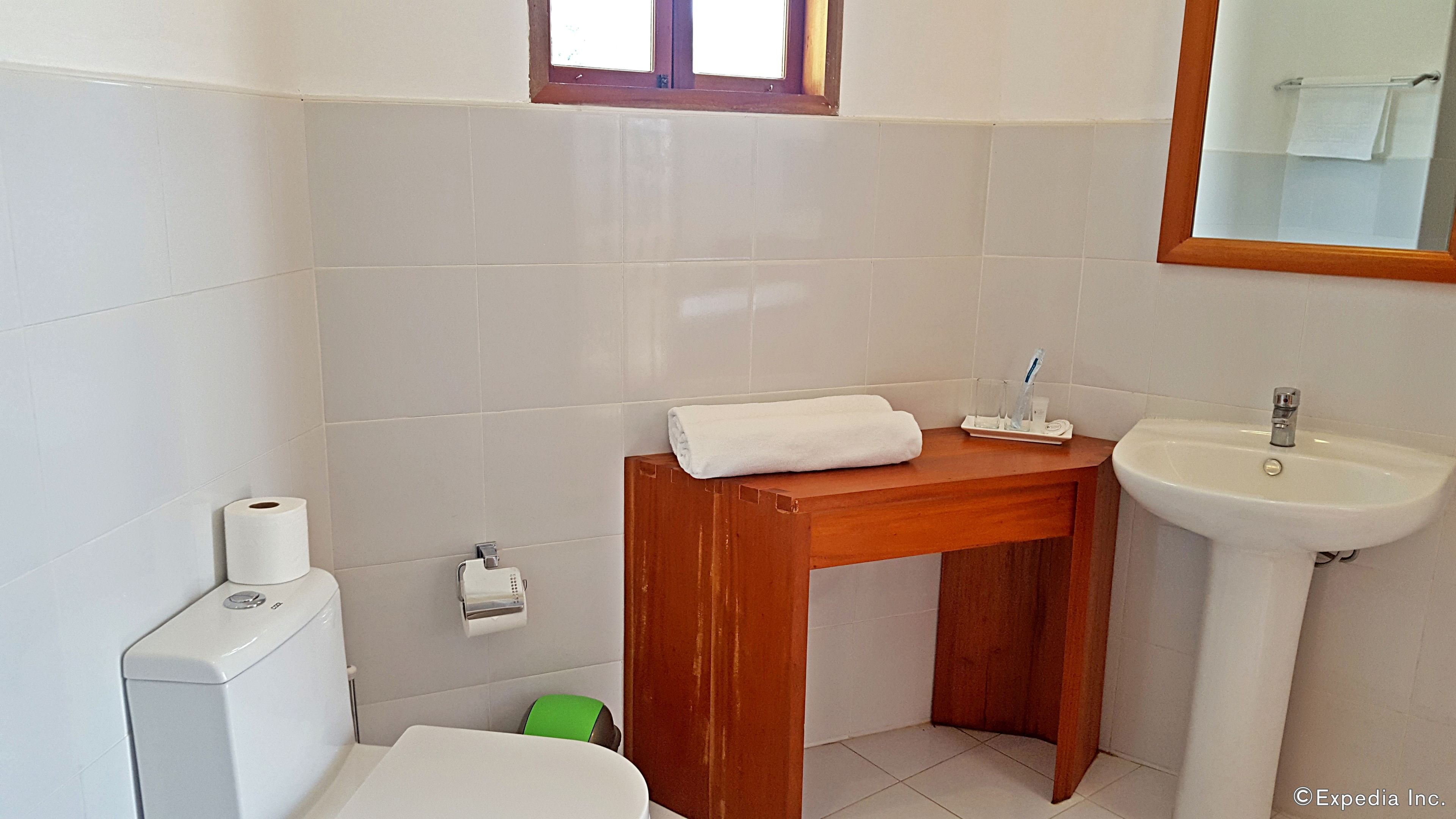 Une salle de bain avec un meuble-lavabo en bois, un lavabo blanc et des toilettes.
