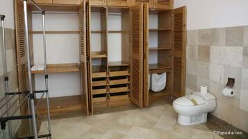 Une salle de bain avec des meubles en bois, des toilettes et une étagère en métal.