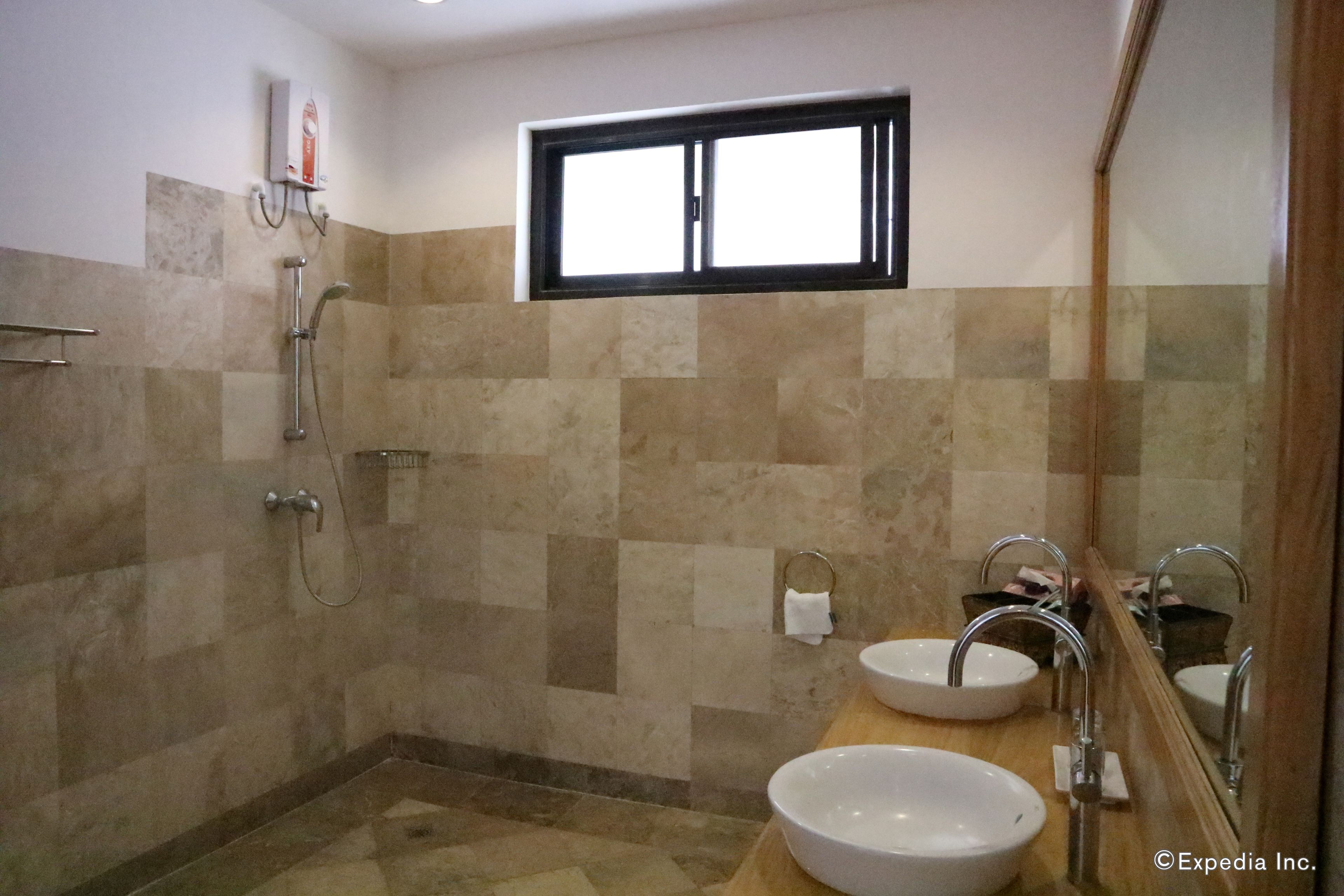 A bathroom with two sinks, a shower, and a window.