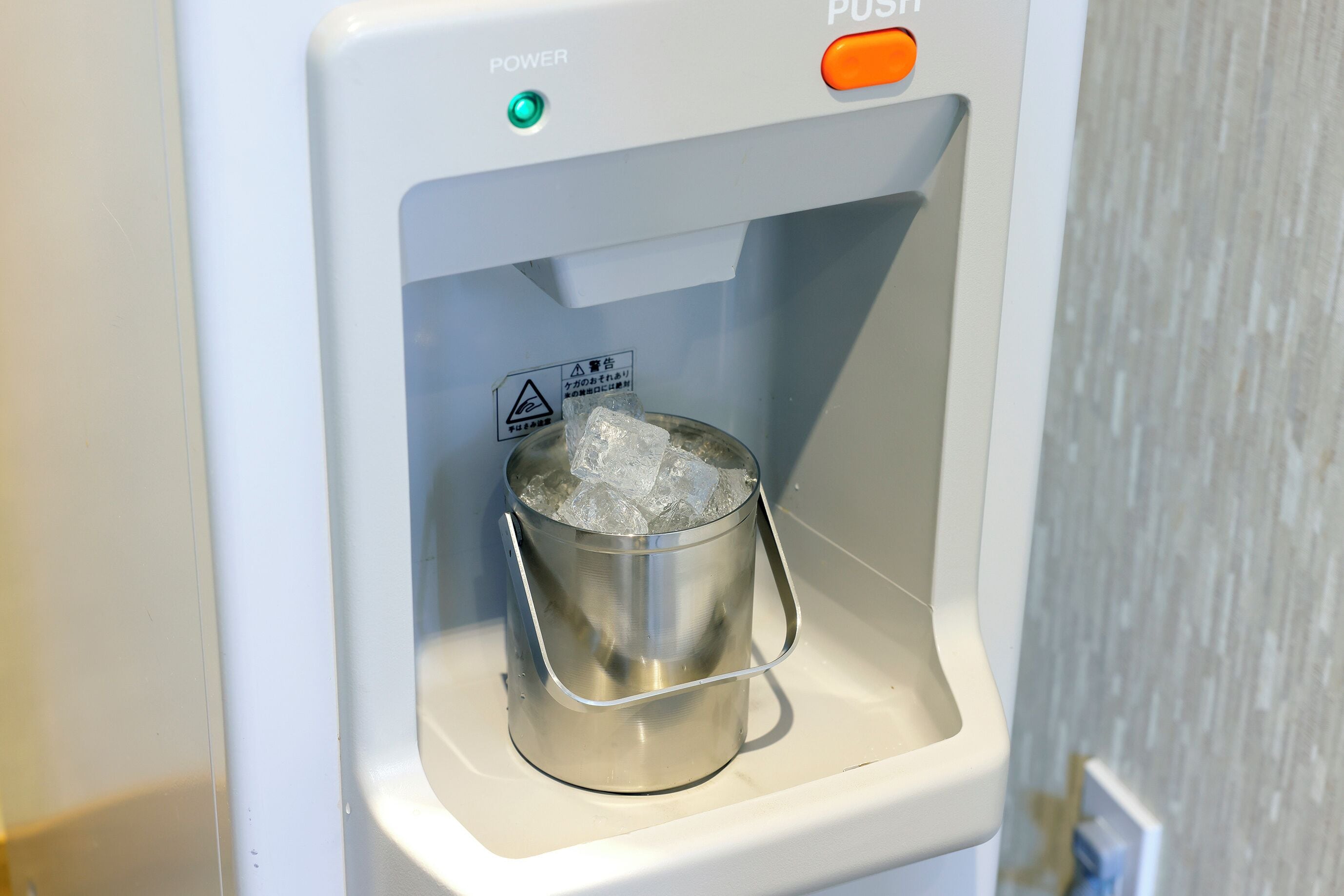 Un dispensador de agua con un cántaro metálico lleno de cubitos de hielo.