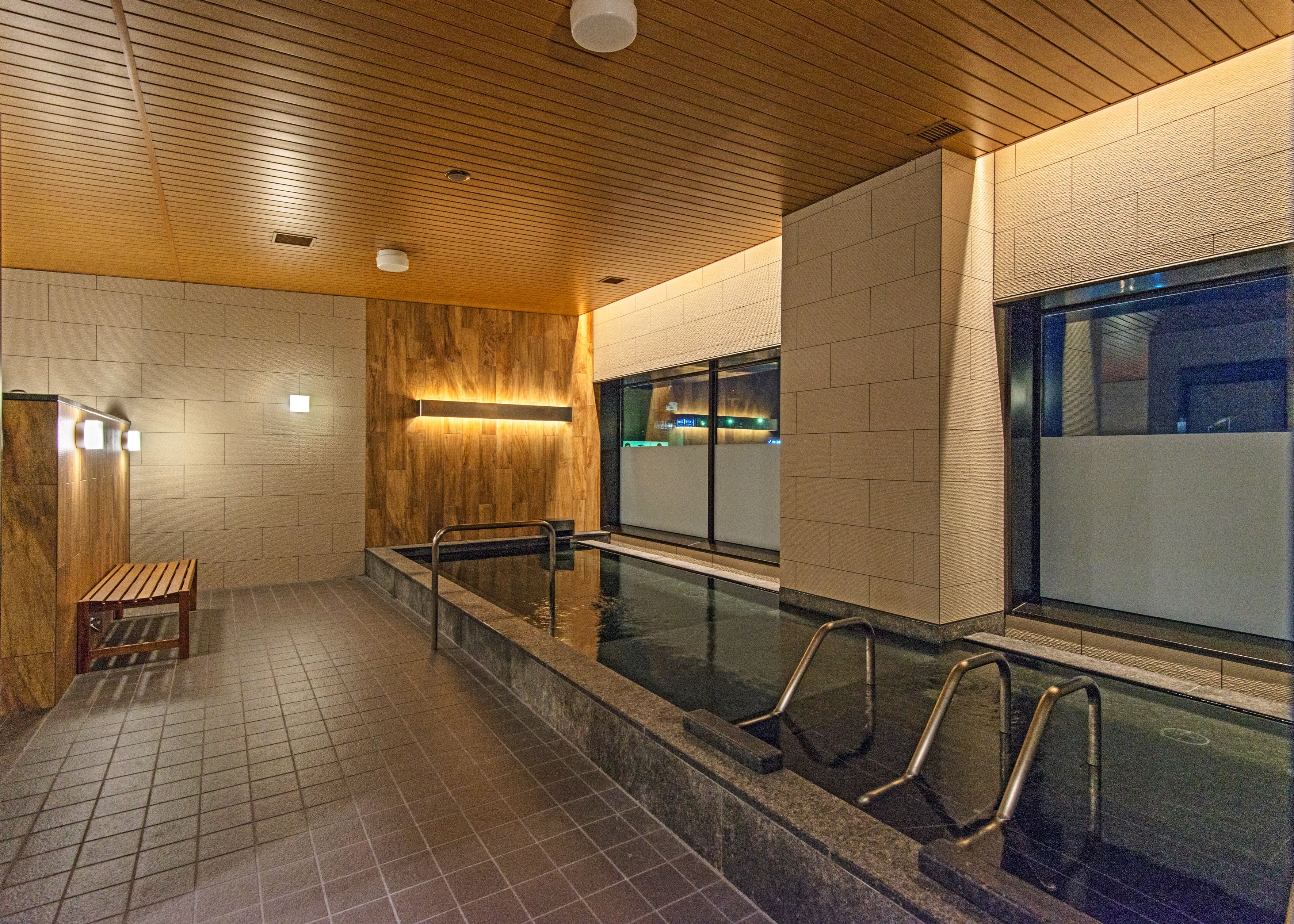 A modern indoor swimming pool with wooden paneling and tiled walls.