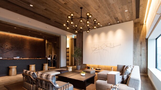 A modern living room with a wooden ceiling, a large chandelier, and a minimalist wall art piece.