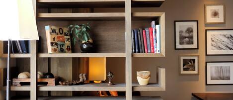 Una estantería de madera con libros, adornos y una pequeña mesa.