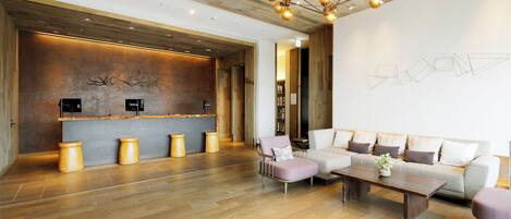 A modern lobby with a reception desk, seating area, and a unique wall art installation.