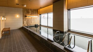 A modern indoor pool area with wooden ceiling, tiled floor, and a bench.