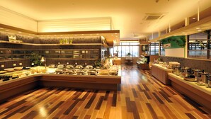 A spacious kitchen with a central island, wooden flooring, and a view of the city through large windows.