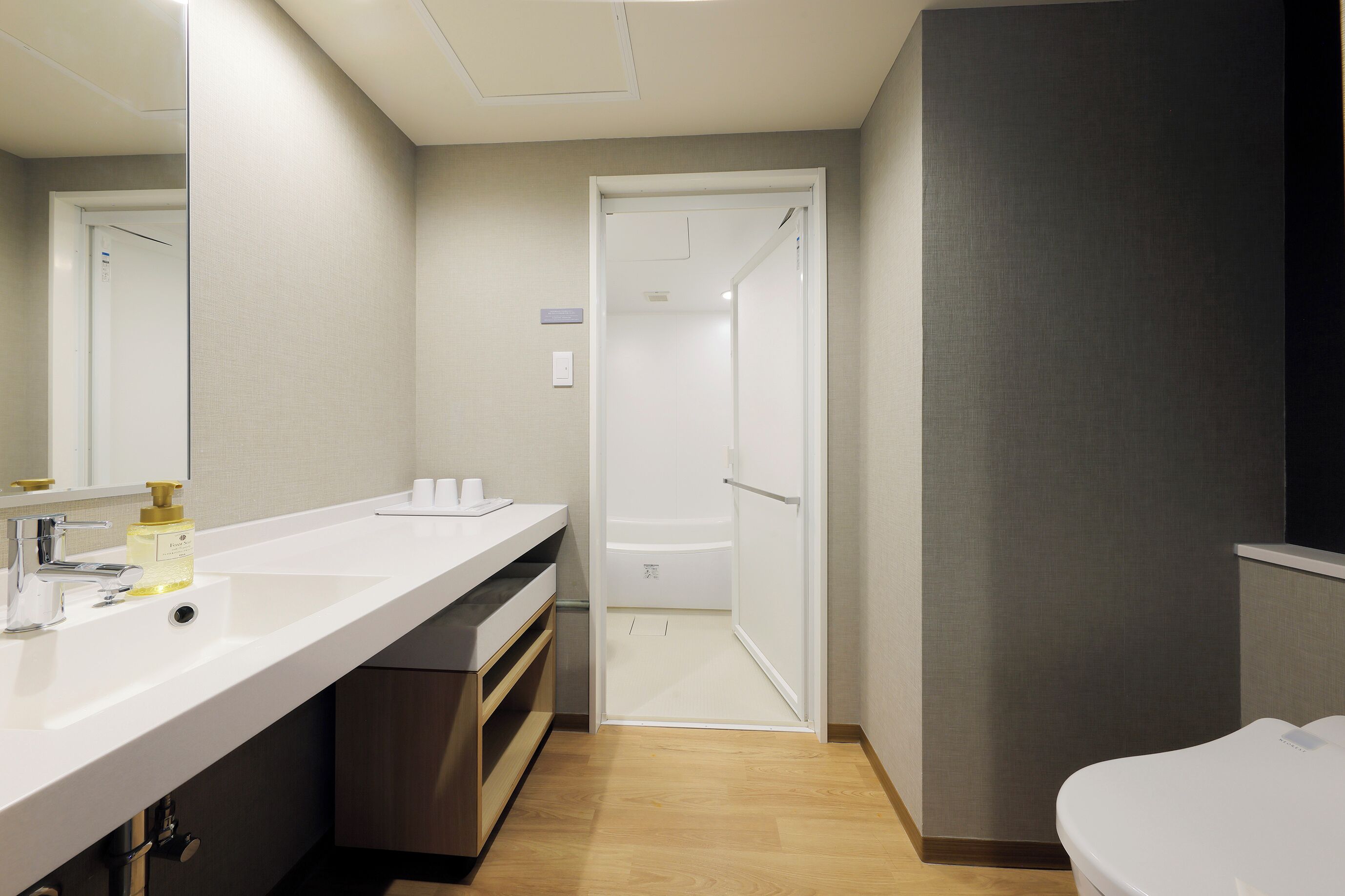 Ein modernes Badezimmer mit einem weißen Waschbecken, einem Spiegel, einer Dusche und einer Toilette.