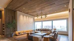 A modern living room with a large sofa, coffee table, and a potted plant.