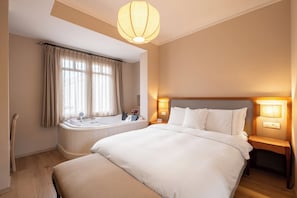 A hotel room with a large bed, a bathtub, a wooden nightstand, and a ceiling light fixture. - Viento Hotel Alacati - Special Class (Cesme)