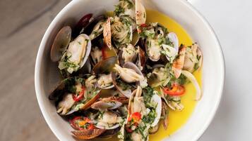 A bowl of clams with herbs and lemon.