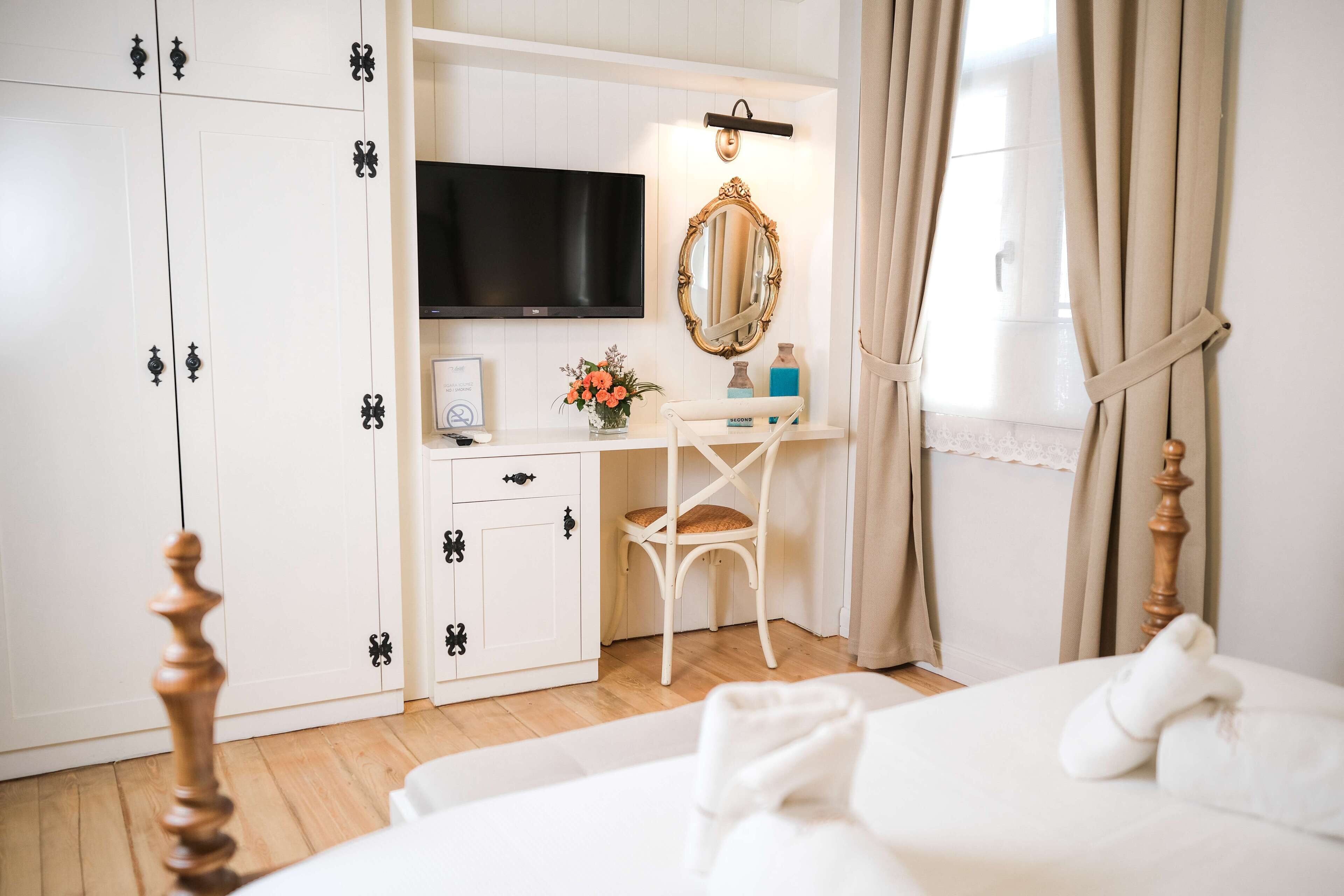 Un dormitorio con cama, escritorio con televisor, espejo y armario.
