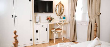 Un dormitorio con cama, escritorio con televisor, espejo y armario.