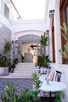 Un patio con zona de estar, plantas en macetas y vista al edificio.