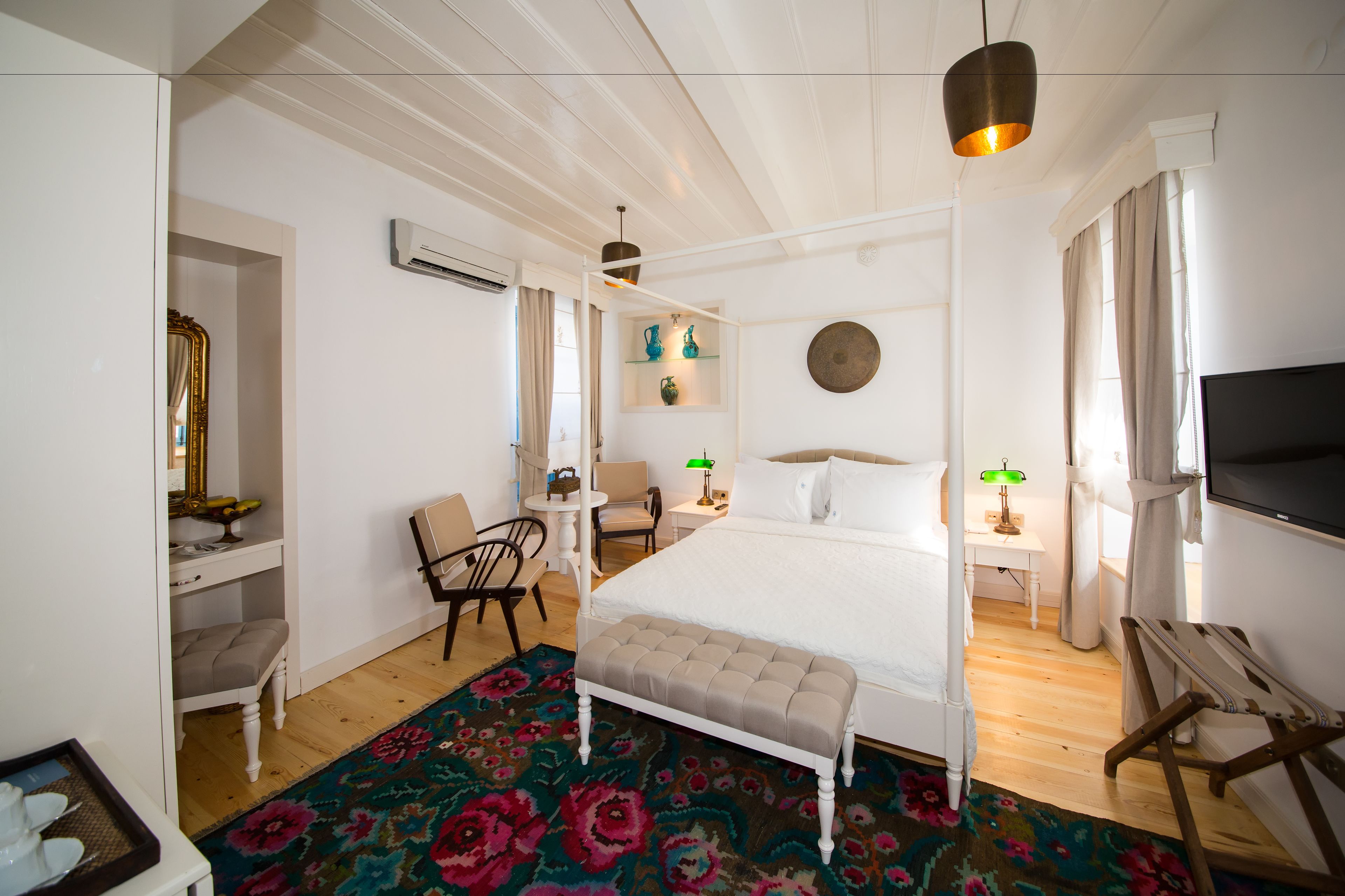 Une chambre à coucher avec un lit, une table de chevet, une chaise et une grande fenêtre.
