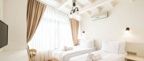 A hotel room with two beds, a desk, and a TV.
