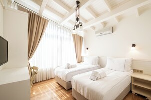 Habitación de hotel con dos camas, un escritorio y un televisor.