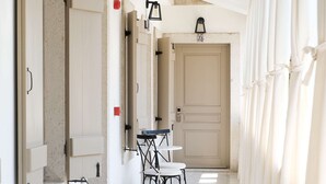 A corridor with doors, a table with chairs, and a patterned floor. - Viento Hotel Alacati - Special Class (Cesme)