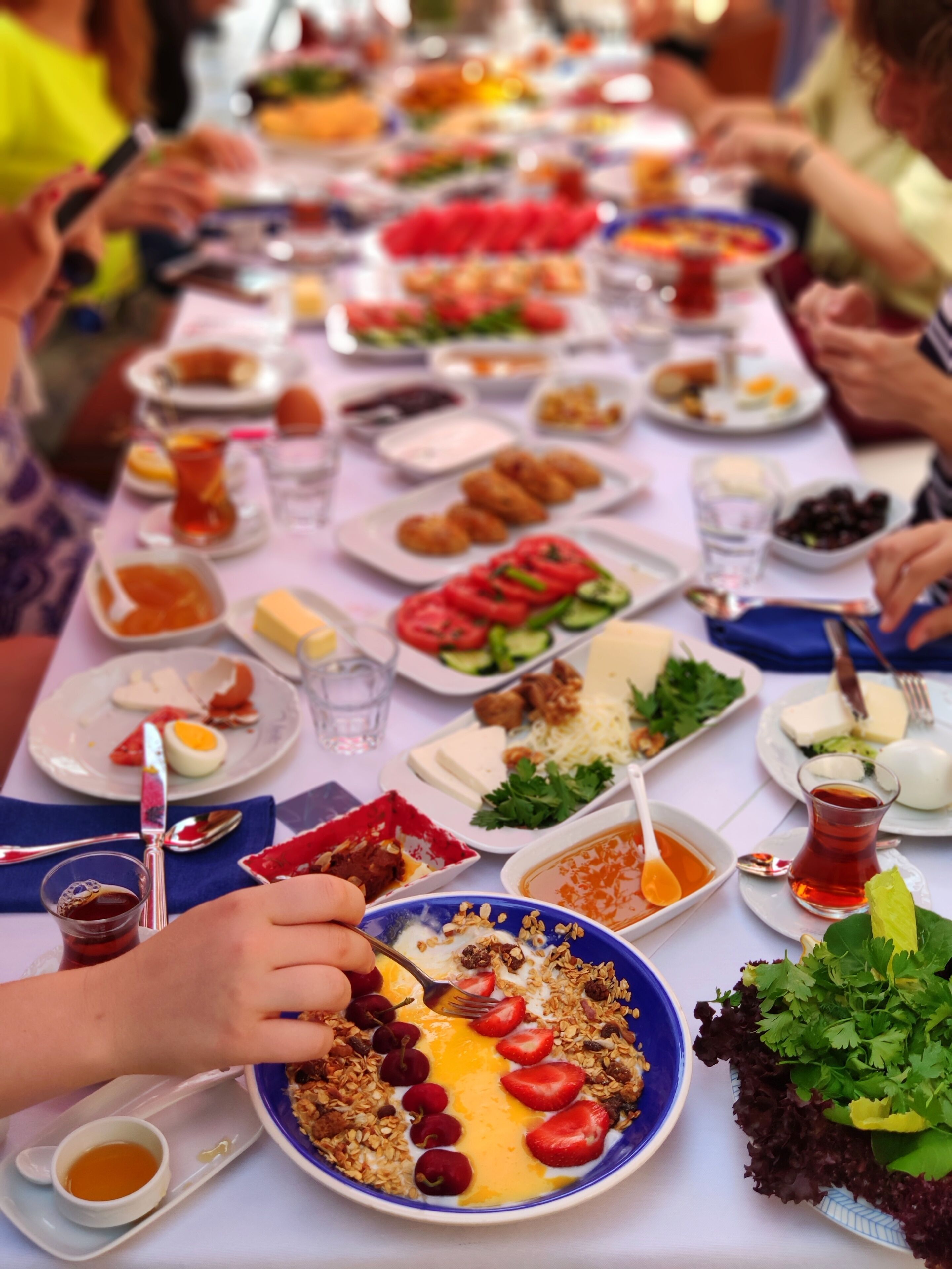 A long dining table with various dishes and drinks, indicating a communal meal setting.