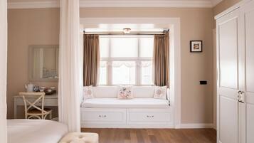A bedroom with a built-in window seat, a bedside table, a mirror, and a wardrobe.