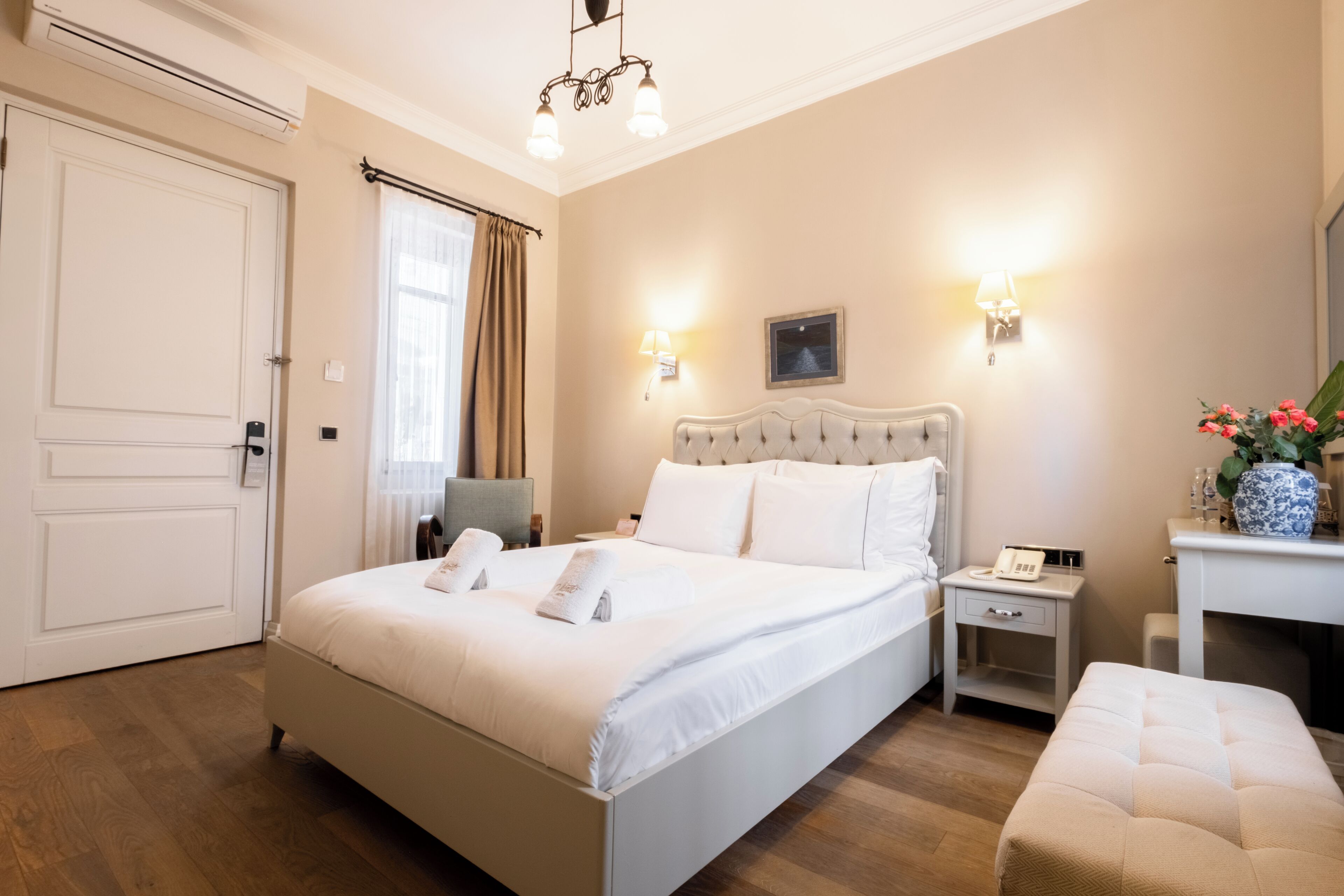 A hotel room with a large bed, bedside tables, a chair, a desk, and a mirror.