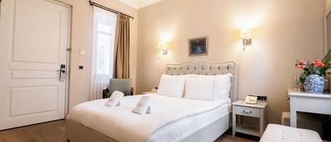 A hotel room with a large bed, bedside tables, a chair, a desk, and a mirror.
