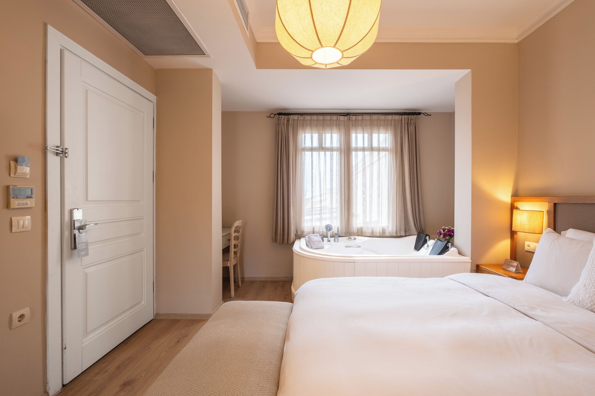 A hotel room with a bed, a bathroom with a bathtub, a desk, and a chair.