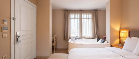 A hotel room with a bed, a bathroom with a bathtub, a desk, and a chair.
