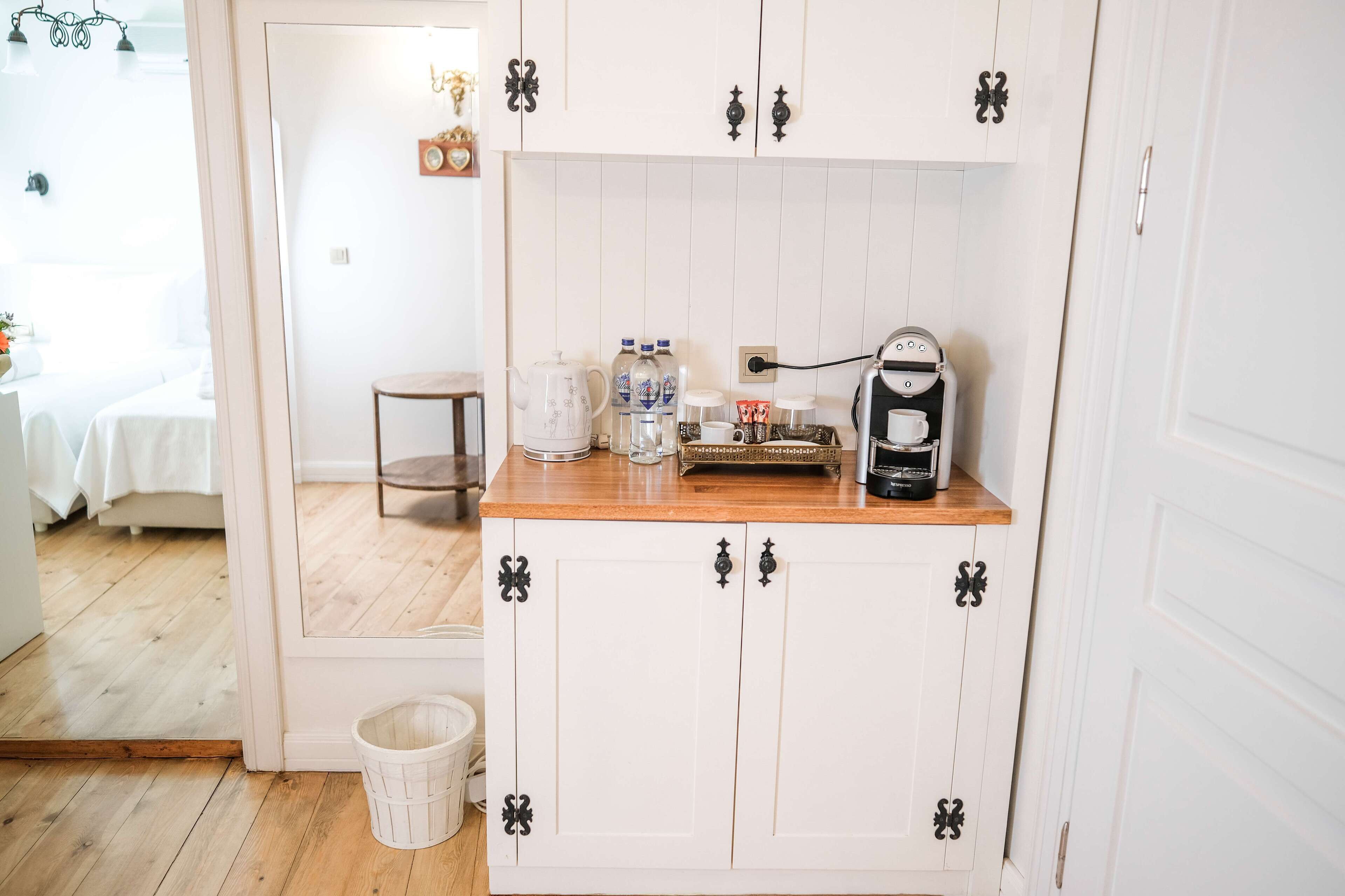 A kitchen with white cabinets, a wooden countertop, and a coffee machine.