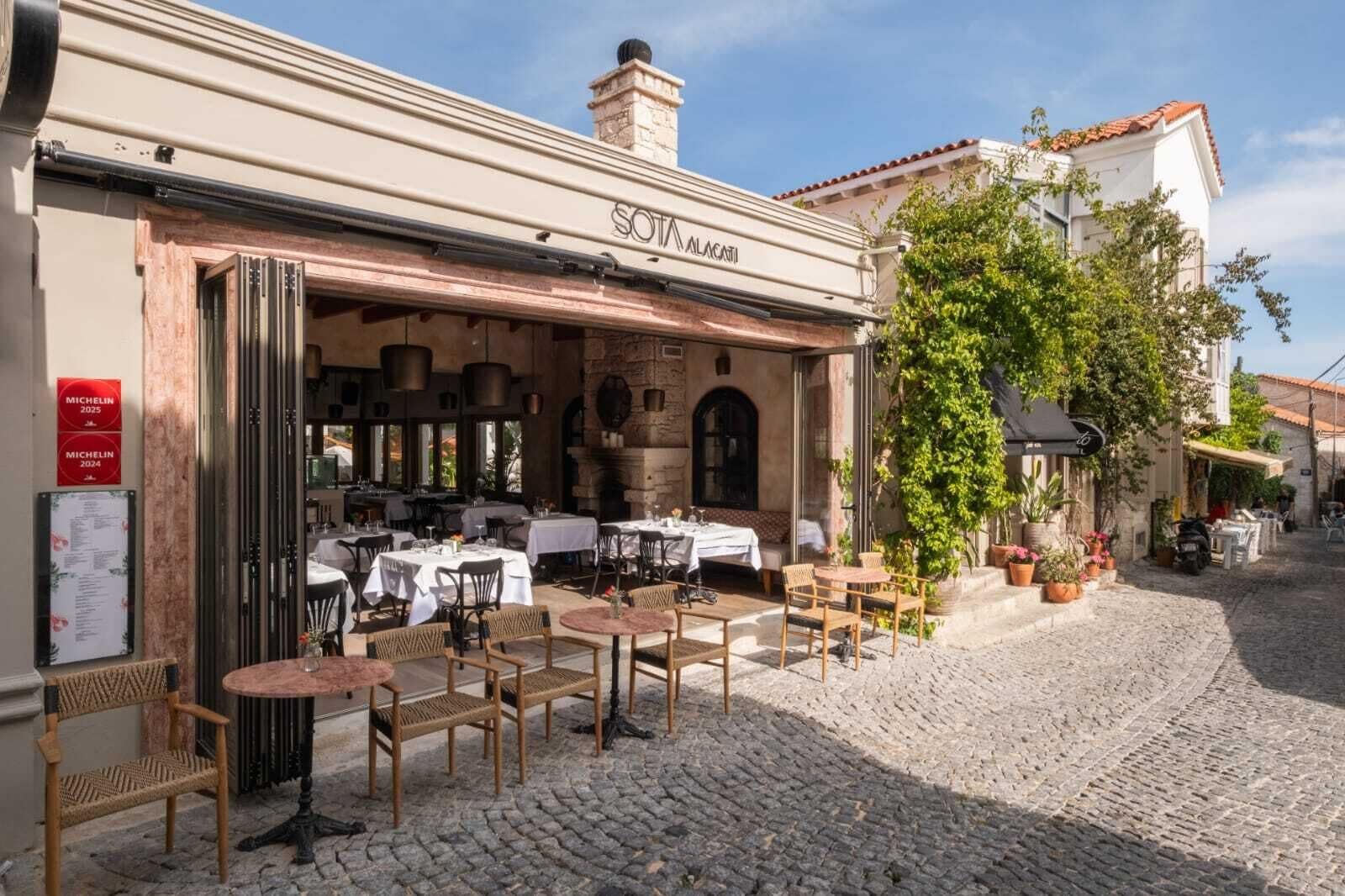 A restaurant with outdoor seating, stone walls, and a cobblestone street.