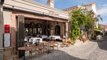 Un restaurante con terraza, paredes de piedra y una calle empedrada.