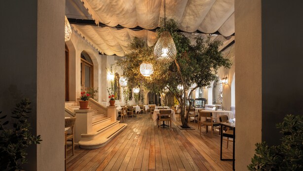 An indoor dining area with wooden flooring, tables, chairs, hanging lights, and potted plants. - Viento Hotel Alacati - Special Class (Cesme)