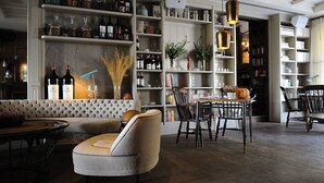 A cozy living area with a sofa, a dining table, and chairs. There are shelves with books and decorative items.