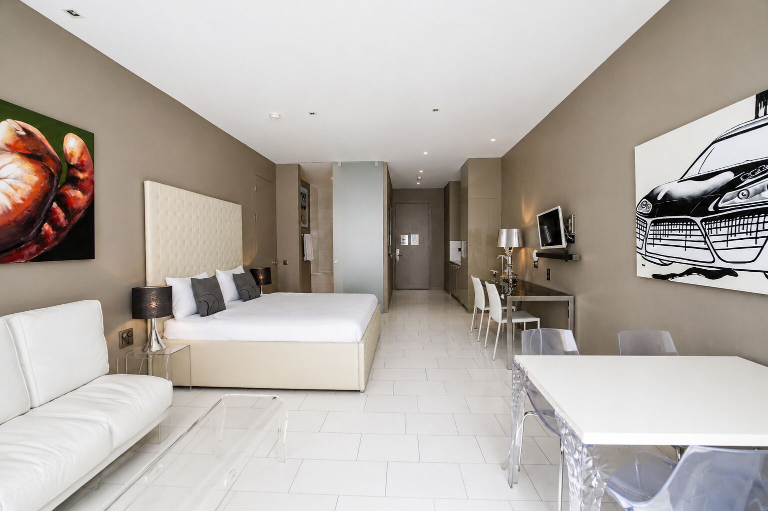 Ein modernes Hotelzimmer mit einem großen Bett, einer Couch, einem Esstisch und einem Fernseher.