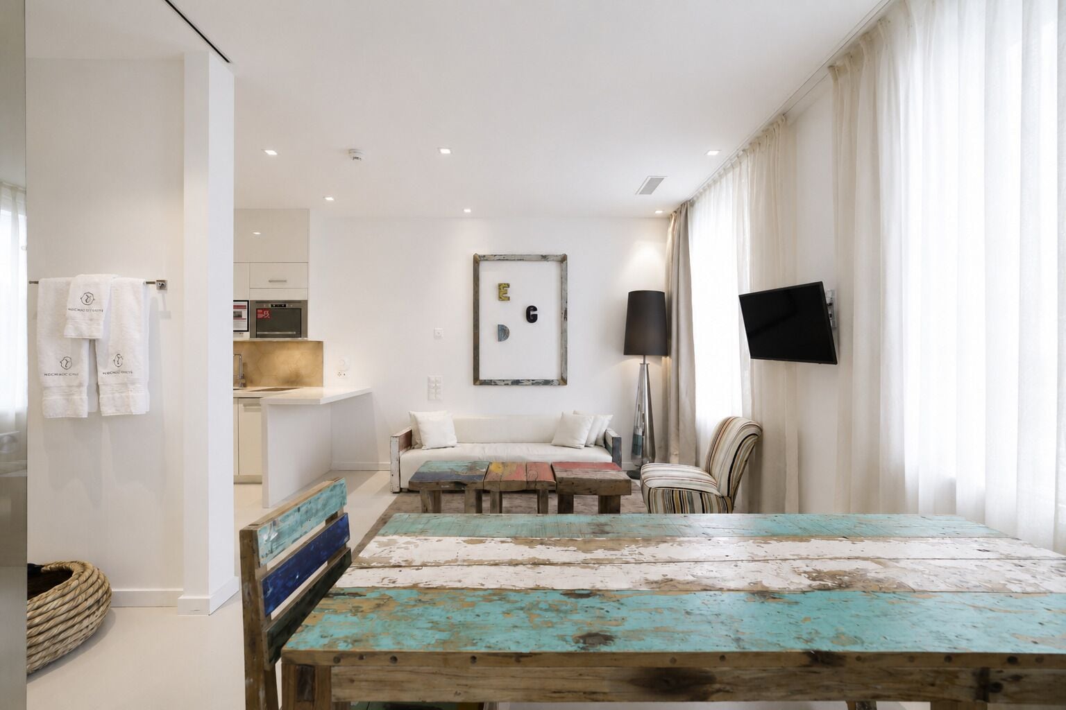 A modern bedroom with a bed, a TV, and a dining table.