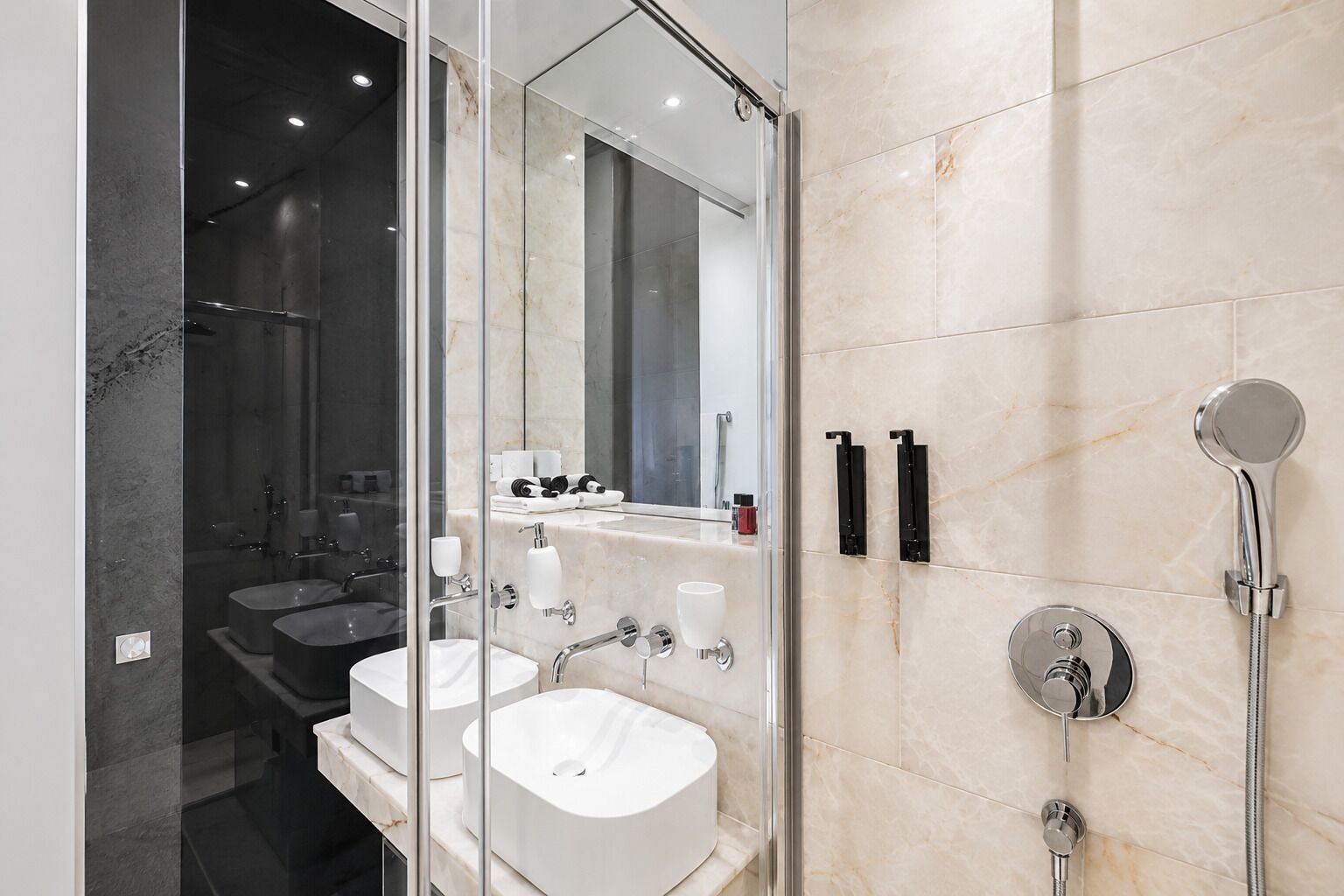 A modern bathroom with two sinks, a glass shower enclosure, and a large mirror.