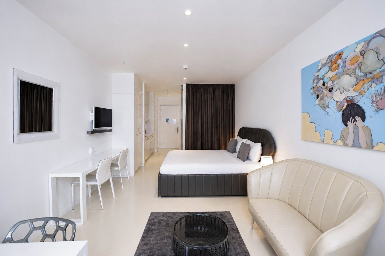 Une chambre d’hôtel moderne équipée d’un lit, d’un canapé, d’un bureau et d’une télévision.