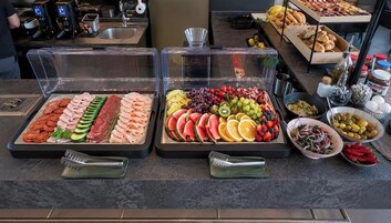 Un bufé con una variedad de alimentos, incluyendo carnes, quesos, frutas y salsas.