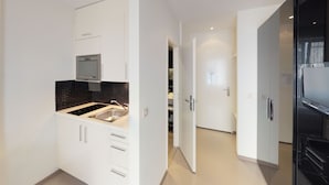A modern kitchen with white cabinetry, a black tiled backsplash, and stainless steel appliances. - VISIONAPARTMENTS Zurich Waffenplatzstrasse (Zürich)