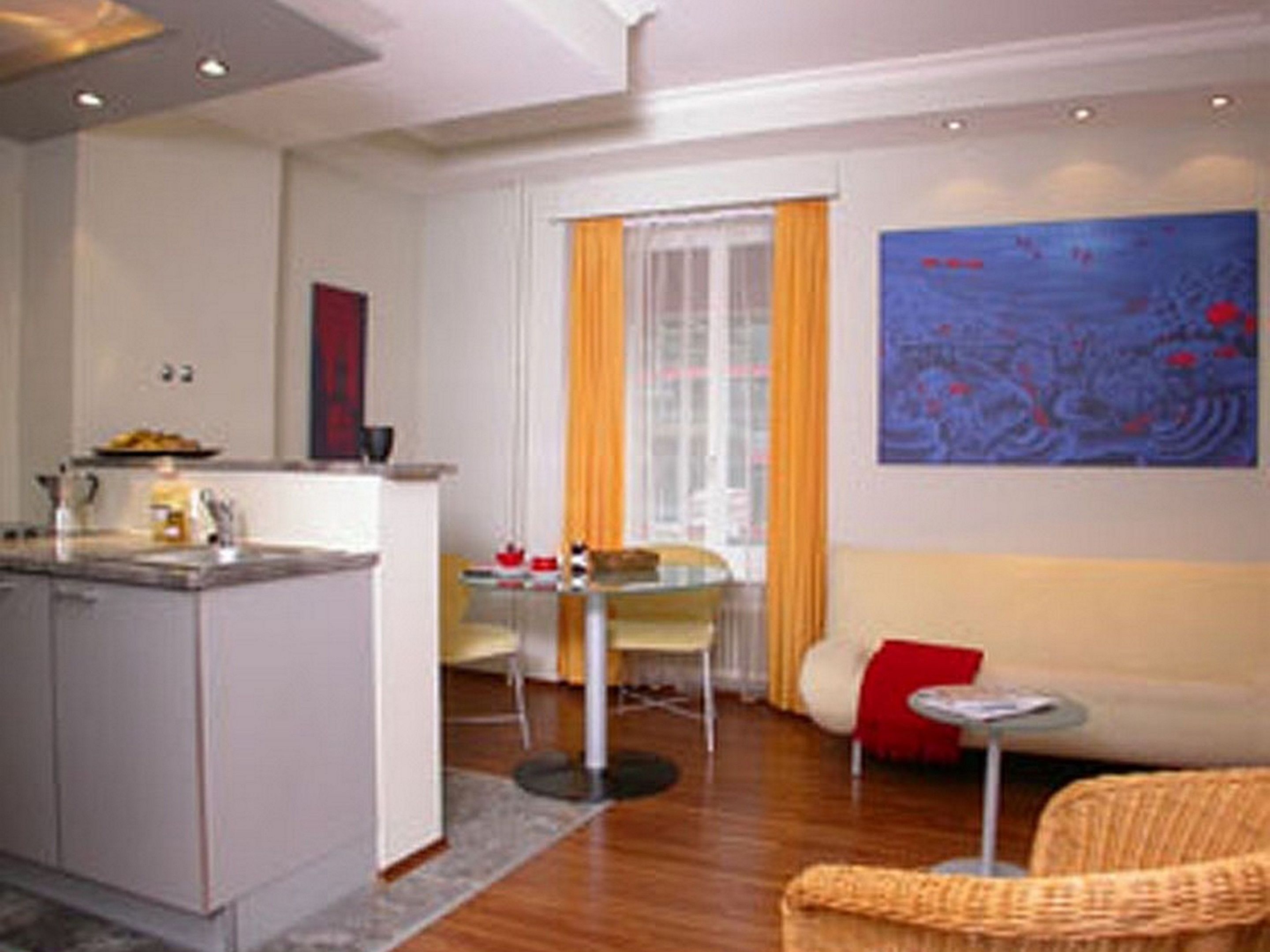 A modern living room with a sofa, a small table, and a dining area with chairs.