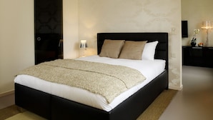 A modern bedroom with a large bed, a bedside table with a lamp, and a small table with a vase and fruit. - VISIONAPARTMENTS Zurich Waffenplatzstrasse (Zürich)