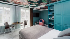 A modern bedroom with a large bed, a desk, and a chair. There is a teal wardrobe and a ceiling mural. - VISIONAPARTMENTS Zurich Albertstrasse (Zürich)