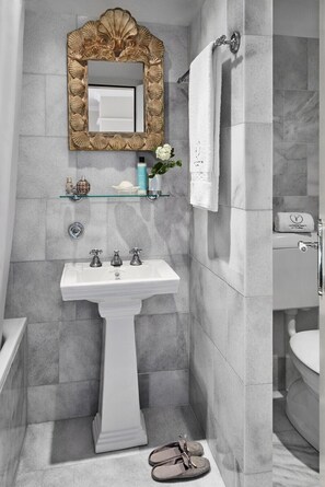 Un bagno con un lavandino su piedistallo, uno specchio decorativo e un porta asciugamani.