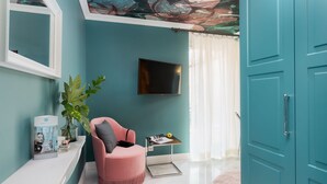 A teal-colored room with a pink chair, a TV, a plant, and a door. - VISIONAPARTMENTS Zurich Albertstrasse (Zürich)